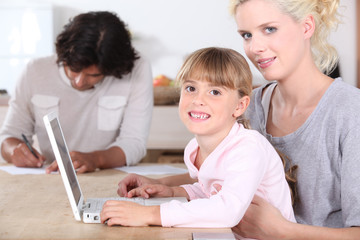 Fototapeta na wymiar Girl using a laptop with her parents