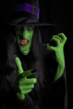 Angry green witch, black background.