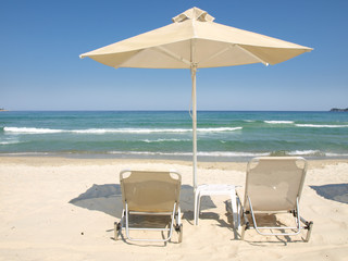 Fototapeta na wymiar Sunchairs and umbrella on Carribean Beach