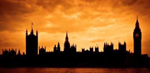 Silhouette of the Houses of Parliament and Big Ben across River Thames in London, UK with dramatic sky during sunset