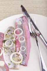Matjes Heringsfilet in roter Beete und mit Gartenkräutern.