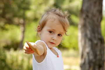 Little girl show you a cracker in the park.