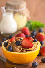 Wholewheat cereal with fruits in a half orange fruit