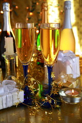 Champagne in glasses,gifts and lights on gold background.