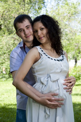 Man and a pregnant woman hugging in the park