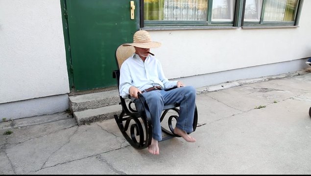 Ein Mann entspannt sich im Schaukelstuhl und raucht Zigarre
