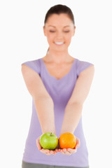 Attractive woman holding fruits while standing