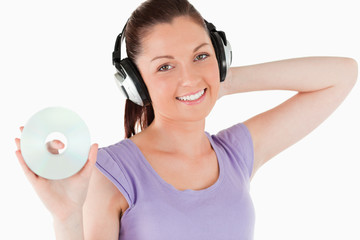 Naklejka premium Charming woman with headphones holding a CD while standing