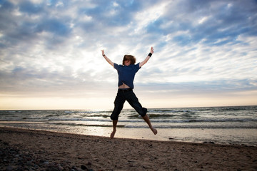 Happy young man jumping on the beach