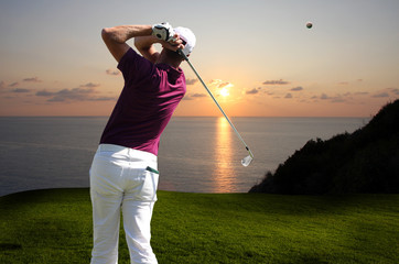Man playing golf against sunset over sea