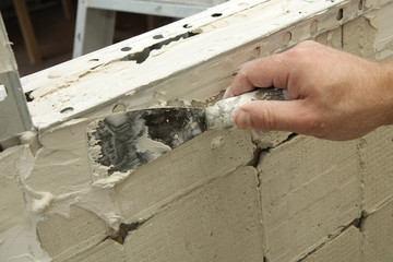 homme enduisant mur de plâtre colle