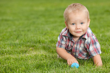 Funny little boy on the green grass