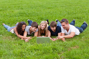 fünf junge leute liegen vor dem notebook