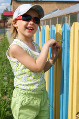 Smiling girl stands near a coloured fence