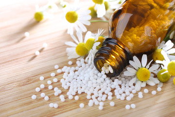 Obraz na płótnie Canvas Homeopatia - globulki z rumianku jako medycyny alternatywnej