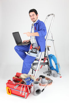 Man Sitting On Ladder With Laptop And Plumbing Tools