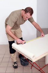 Decorator measuring a roll of wallpaper