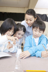 理科の実験をする小学生男女と女性教師