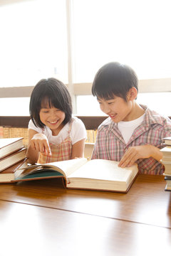 図書室で本を読む小学生男女