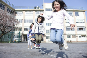 大縄跳びをする小学生と教師