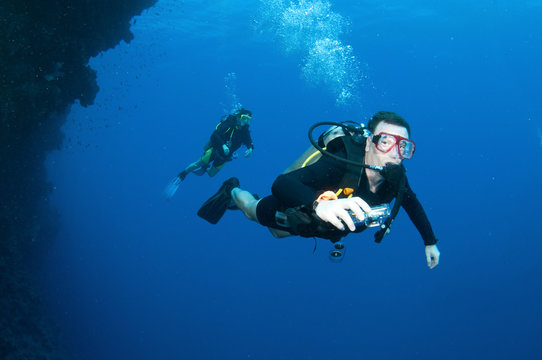 Scuba divers swim underwater in clear blue water © JonMilnes