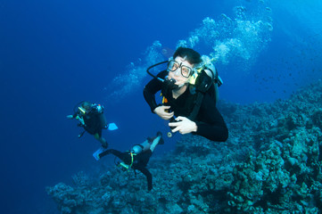 Scuba divers swim underwater in clear blue water