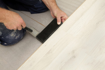 homme posant parquet flottant stratifié avec marteau
