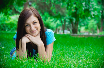 Naklejka na ściany i meble Portrait of a happy young woman lying on grass