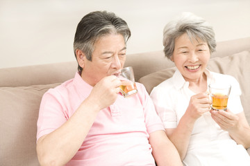 ソファに座りアイスティーを飲む老夫婦