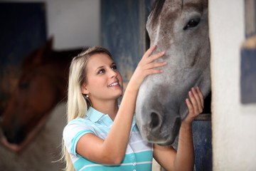 Blond teenage girl stroking horse
