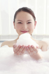 お風呂の泡を手に持つ女性