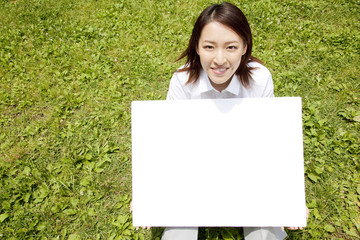 公園でメッセージボードを持つOL