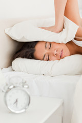 Obraz na płótnie Canvas gorgeous woman waking under sheet not wanting to hear alarm cloc