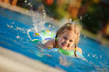 cute toddler girl splashing in outdoor pool