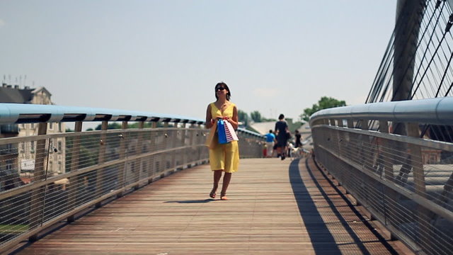 Attractive woman with shopping bags on the bridge, slow motion
