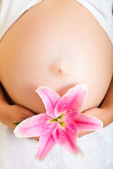 Pregnant woman holding lillies isolated on white