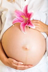 Pregnant woman holding lillies isolated on white