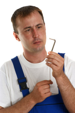 Handwerker mit blauer Latzhose hält einen Inbusschlüssel