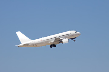 A white passenger plane flies into a blue sky.