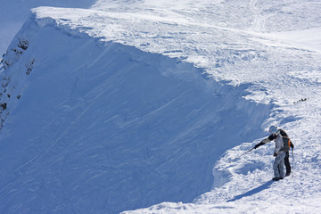 Two ski freeriders are standing on the brink of a precipice.