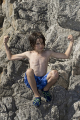 Junge sitzt am Meer auf Felsen