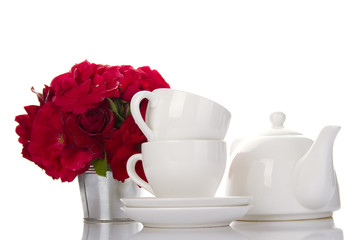 White crockery for tea and a bouquet of roses