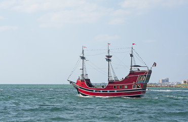 A red pirate ship at sea.