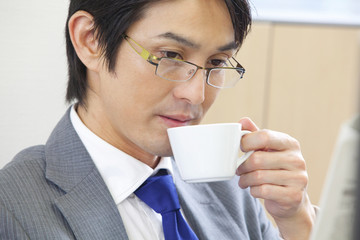 新聞を読みながらコーヒーを飲むビジネスマン