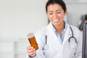 Attractive smiling doctor holding and looking at a box of pills