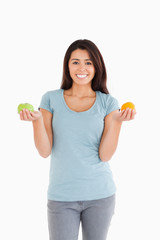 Attractive woman holding an apple and an orange