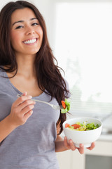 Pretty woman enjoying a bowl of salad while standing