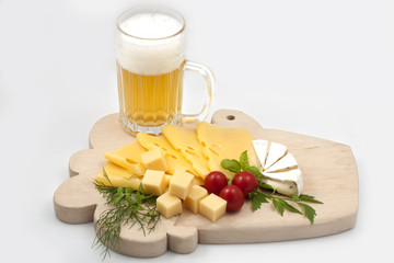 Various types of cheese on a wooden board with beer