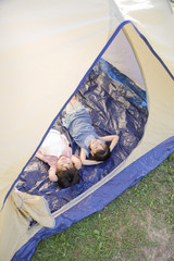テントに寝転んで空を見上げる男の子と女の子