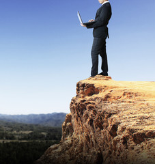 Business man using a laptop on a rock